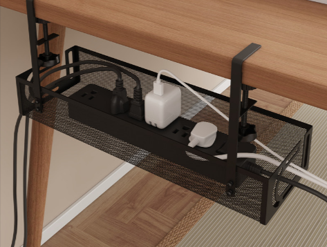 Under-Desk Cable Tray, black steel mesh, clamped under a desk edge. The power strip and chargers shown are for illustration and are not included