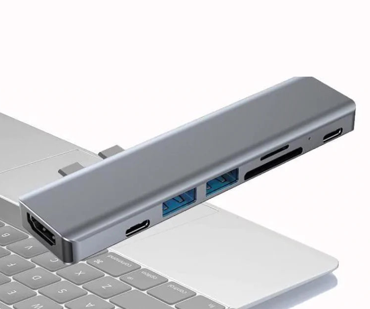 USB-C 7-in-1 Hub, port side: HDMI, two USB-C, two USB-A, and SD and microSD slots, shown above a laptop keyboard